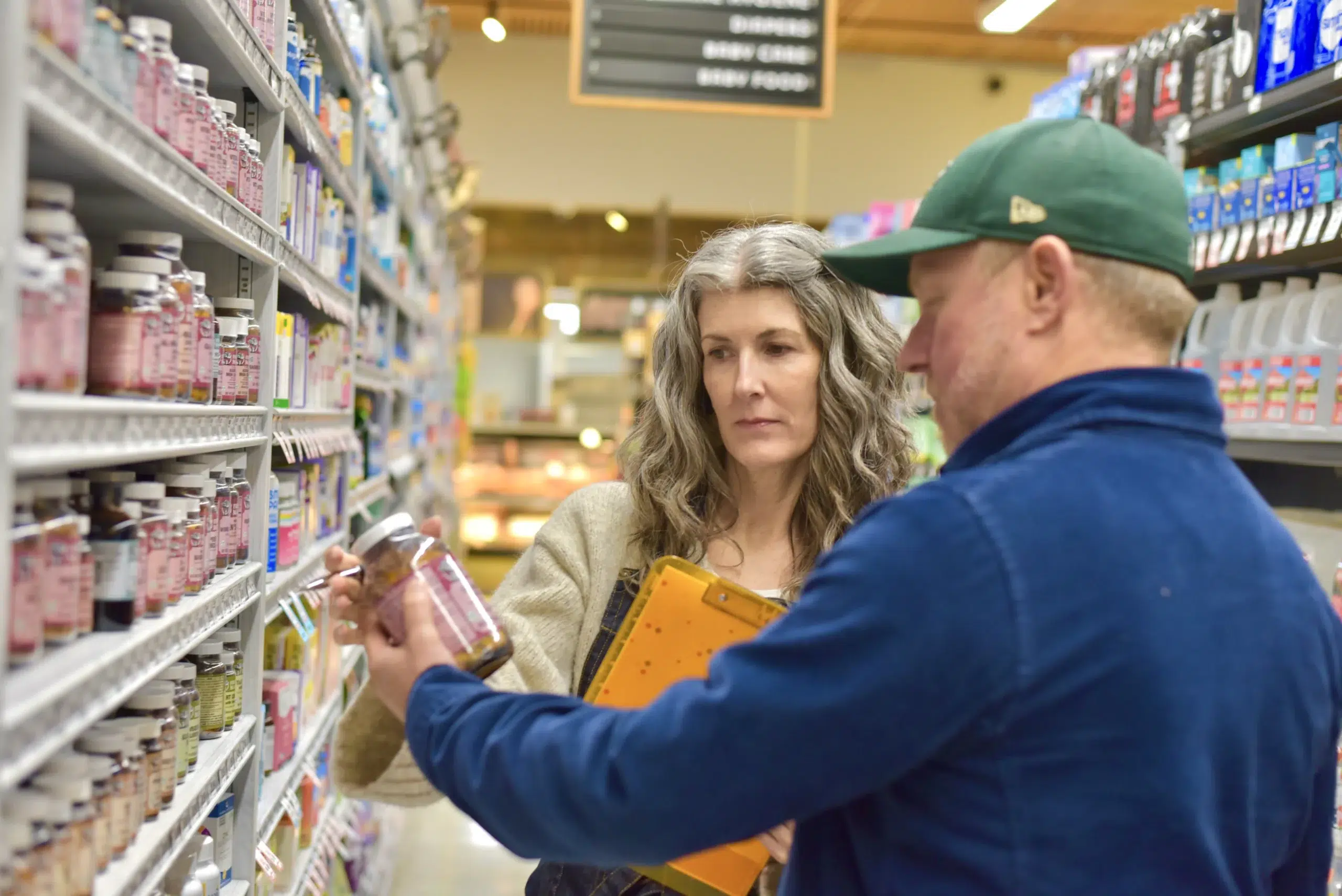 Two people discussing products in a natural products store aisle.